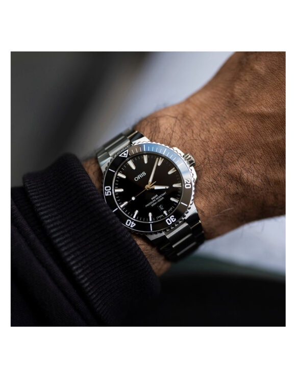 Oris Aquis Date indossato al polso con bracciale in acciaio e quadrante nero