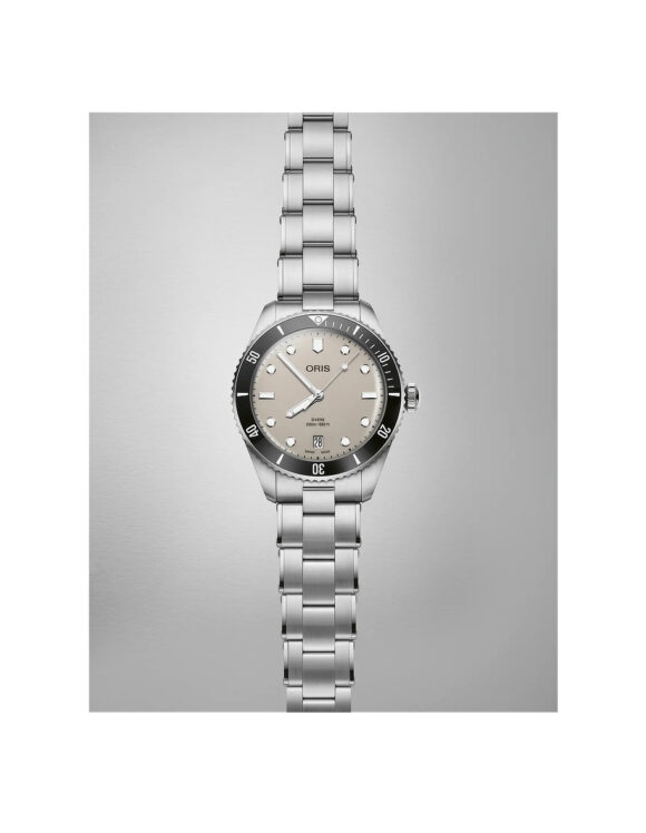 Oris Divers Date quadrante beige, orologio disteso con bracciale in acciaio su superficie neutra